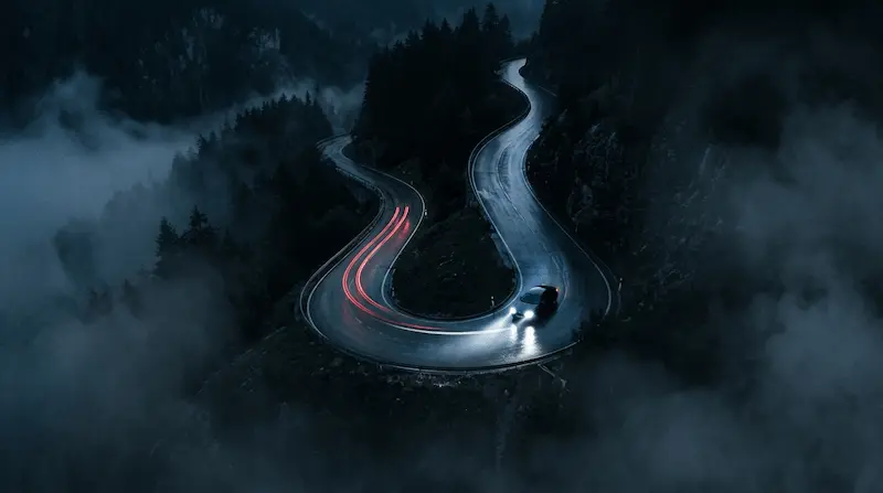"A dark winding road at night with a single pair of headlights representing HANRORO Our Goodbye from Perfect Crown OST"