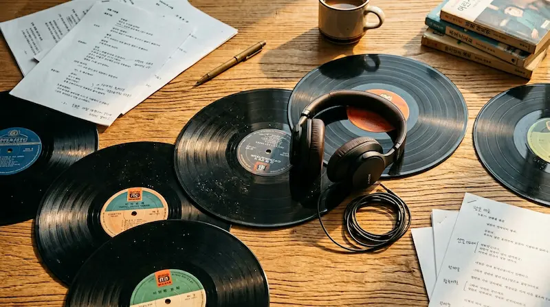 Best K-drama OST songs — vinyl records and headphones on a warm wooden table