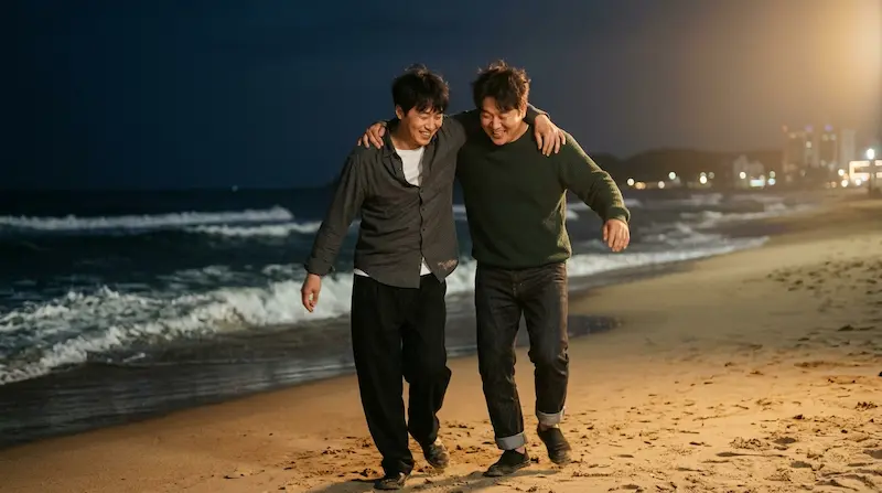 Hwang Dong-man (Koo Kyo-hwan) and Park Gyeong-se (Oh Jung-se) dance with arms over each other's shoulders by the night sea in We Are All Trying Here Episode 7.